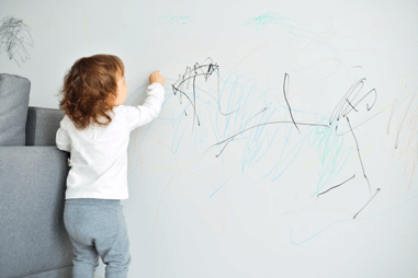 Image of a kid drawing on a wall